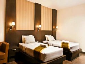 una camera d'albergo con due letti e una sedia di STEFANI MAKATI HOTEL a Pekanbaru