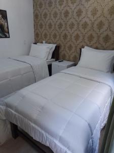 Casa Amarela Pousada في دومينغوس مارتينز: سريرين في غرفة الفندق ذات شراشف بيضاء