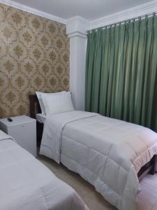 ein Schlafzimmer mit 2 Betten und einem grünen Vorhang in der Unterkunft Casa Amarela Pousada in Domingos Martins