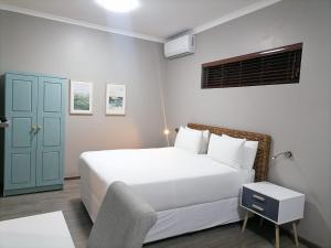 a bedroom with a white bed and a blue door at HWH Guesthouse Middelburg in Middelburg