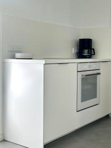 a white kitchen with a stove and a microwave at Heide Apartments in Schneverdingen +22 photos