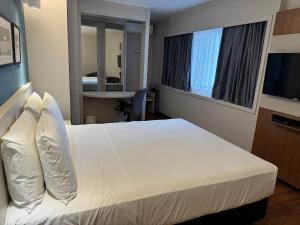 a hotel room with a white bed and a table at Flat Particular no Comfort Suites in Brasilia