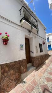 Edificio blanco con balcón y puerta en Casa Miguelito en Comares