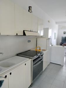 a white kitchen with a stove and a sink at Sunny House in Parghelia