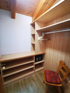 a room with wooden walls and a chair and shelves at Gästehaus Thaler in Mittelberg