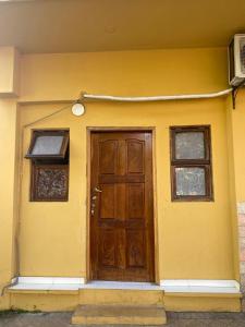 ein gelbes Haus mit einer Holztür und zwei Fenstern in der Unterkunft Villa Morra House in Asunción