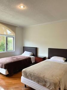 1 dormitorio con 2 camas y ventana en Departamento Amplio En El Centro De Otavalo en Otavalo