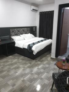a bedroom with a large bed and a table at Downunder suites in Gwarinpa