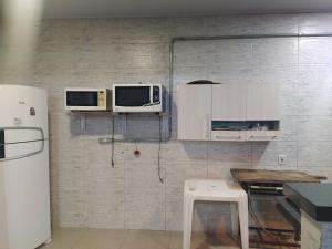 - une cuisine avec 2 fours micro-ondes sur un mur dans l'établissement Piscina, Hidro, churrasqueira em casa, ambas privativas - Reserva 2 quartos com ar, 2 banheiros, sala,cozinha e pátio privativos, para moradia memorável ou evento, acesse descontão por duração!, à Sorriso