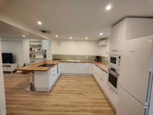 una grande cucina con mobili bianchi e pavimento in legno di RDC T4 Maison proche Aéroport a Saint-Laurent-de-Mure