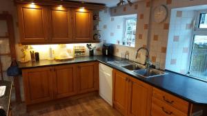 a kitchen with wooden cabinets and a sink at Moonraker Room with a View with ensuite shower room in St Austell