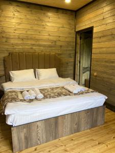 uma cama num quarto de madeira com chinelos em Balkonchik GuestHouse em Dilijan