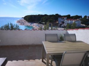 uma mesa de madeira e cadeiras numa varanda com vista para uma praia em Apartments Martin em Primošten