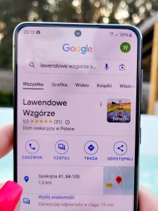 una mano sosteniendo un teléfono celular con la página web de Google en Domek wakacyjny, nad morzem z balią, Lawendowe Wzgórze, en Karwieńskie Błoto Pierwsze