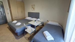 a room with two beds and a table and a desk at Studios Voula in Malakóndas +22 photos