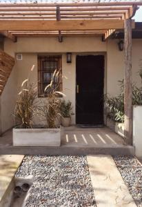 una casa con una puerta negra y algunas plantas en Brisa en San Antonio de Areco