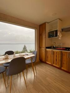 a kitchen and dining room with a table and a large window at ApartHotel Kintumay in Puerto Varas