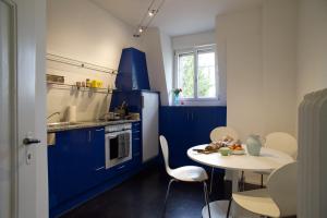 eine Küche mit blauen Schränken und einem Tisch mit Stühlen in der Unterkunft artroom in Bern