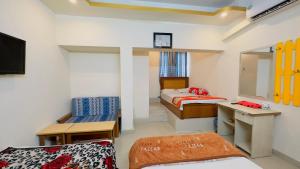 a room with two beds and a desk and a mirror at Hotel Panthapath Dhaka in Dhaka