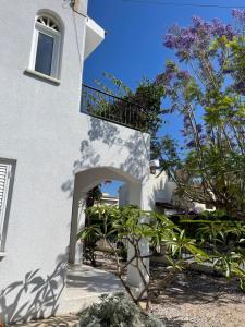 un edificio blanco con balcón y un árbol en Coral Bay Villa Daniella, en Bahía de Coral