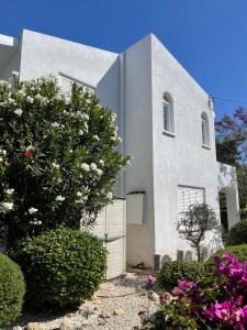 una casa blanca con una puerta y flores en Coral Bay Villa Daniella, en Bahía de Coral