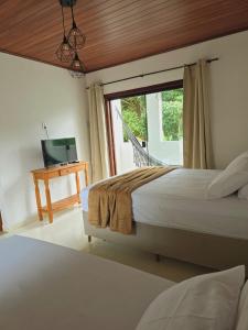 a bedroom with a bed and a television and a window at Chalé Premium no Centro da Vila in Itaúnas