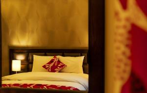 uma cama com almofadas vermelhas e brancas num quarto em Shams Alweibdeh Hotel Apartments em Amã