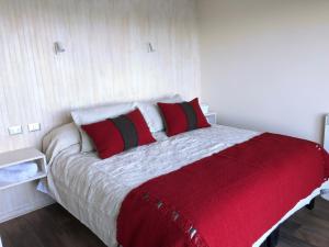 um quarto com uma cama com almofadas vermelhas e brancas em ApartHotel Kintumay em Puerto Varas
