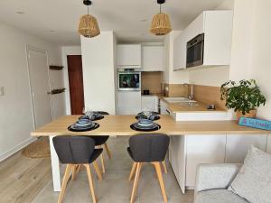 a kitchen with a wooden table and chairs at Le Capitole - Studio d'exception accès direct à la plage Benoît in La Baule