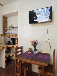Casa Donaji في مدينة أواكساكا: طاولة مع إناء من الزهور وتلفزيون على الحائط