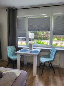 Habitación con mesa, 2 sillas y 2 ventanas en Apartmenthaus am Park, en Wilhelmshaven