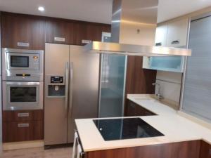 una cocina con electrodomésticos de acero inoxidable y armarios de madera en Apartamento 3 dormitorios en San Vicente del Raspeig