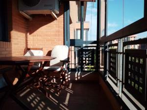 balcón con mesa de madera y 2 sillas en Apartamento 3 dormitorios en San Vicente del Raspeig