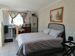 a bedroom with a bed and a kitchen with a refrigerator at Charlie's Spot - Norwood in Johannesburg