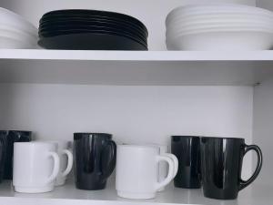 une étagère remplie de tasses et d'assiettes en noir et blanc dans l'établissement Da! Hostel, à Bishkek