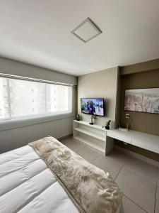 a bedroom with a bed and a flat screen tv at Flat Premium Recife - Ilha do leite piscina termica in Recife +26 photos