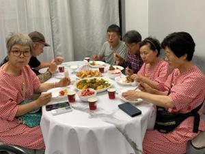Un groupe de personnes assises à une table et mangeant de la nourriture dans l'établissement Da! Hostel, à Bishkek