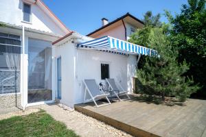 a patio with two chairs and a blue and white umbrella at Будинок біля моря з басейном Одеса для 7 гостей - 3 спальні in Odesa
