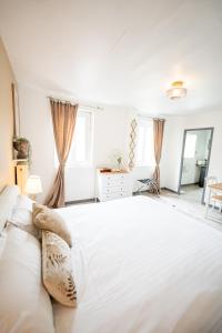 a white bedroom with a large bed and a mirror at Villa Vichéia - Appartement 33 in Vichy