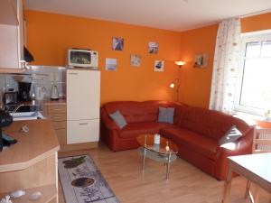 a living room with a red couch and a kitchen at Ferienwohnung Klabautermann in Putbus