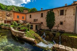 a house with a river in front of a building at Casa Vacanze Fonte del Menotre in Foligno