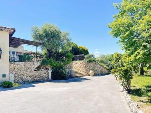 a house with a stone wall and a driveway at Villa Les Reflets - Lac, Vue panoramique, piscine in Montauroux