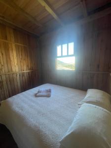 a bed in a wooden room with a window at Casa de Campo Gralha Azul in Bom Jardim da Serra