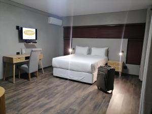 米德爾堡的住宿－HWH Guesthouse Middelburg，酒店客房带一张床和一张带手提箱的书桌