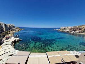 - une vue sur la plage, l'océan et les bâtiments dans l'établissement Attard Seafront Apartment 3 in Marsalforn, à Żebbuġ
