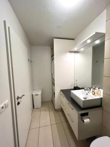 a white bathroom with a sink and a mirror at Comfy flat in Kópavogur in Reykjavík