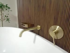 a bathroom sink with a gold faucet on a wall at HWH Guesthouse Middelburg in Middelburg
