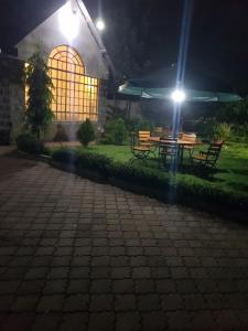 a table and benches in front of a building at night at Teresita Home in Nairobi