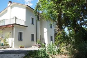 ein weißes Haus mit Bäumen davor in der Unterkunft Casale Mongiusti 1961 in Musano