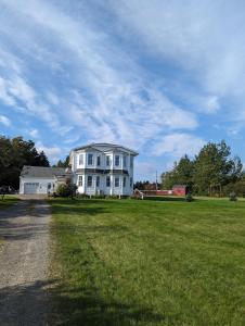 una gran casa blanca en un campo de hierba en The Parrsboro Mansion Inn, en Parrsboro